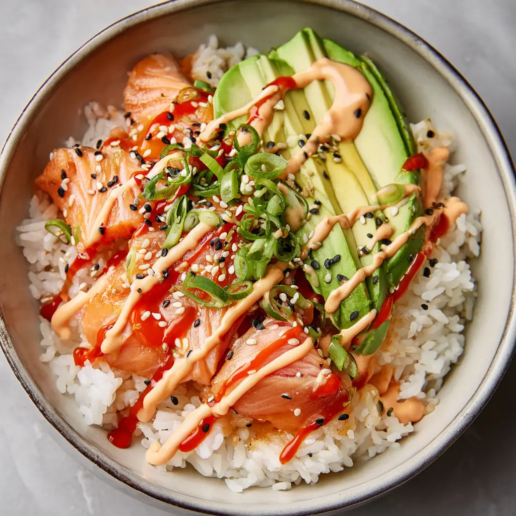Ingredients for a salmon rice bowl including fresh salmon fillets, jasmine rice, fresh green avocado, sriracha, mayonnaise, and black and white sesame seeds.