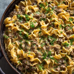 Thick wavy egg noodles thoroughly coated in a glossy, light brown, creamy savory sauce with ground beef crumbles.