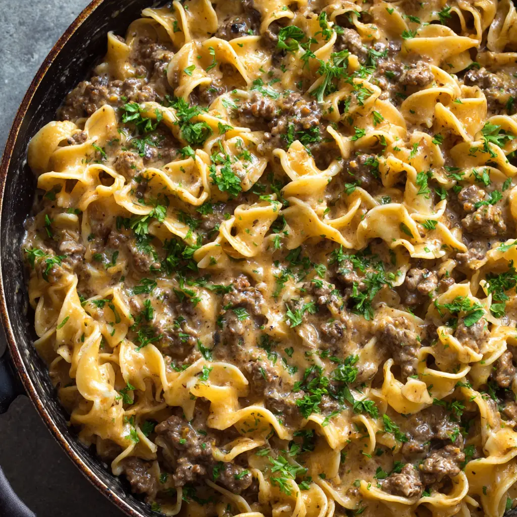 Thick wavy egg noodles thoroughly coated in a glossy, light brown, creamy savory sauce with ground beef crumbles.