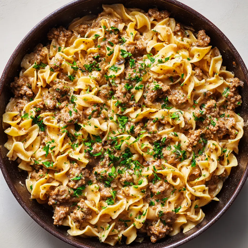The Ultimate One Pan Ground Beef Stroganoff 1 Caramelized browned ground beef crumbles intermixed with creamy stroganoff noodles and garnished with fresh green parsley.