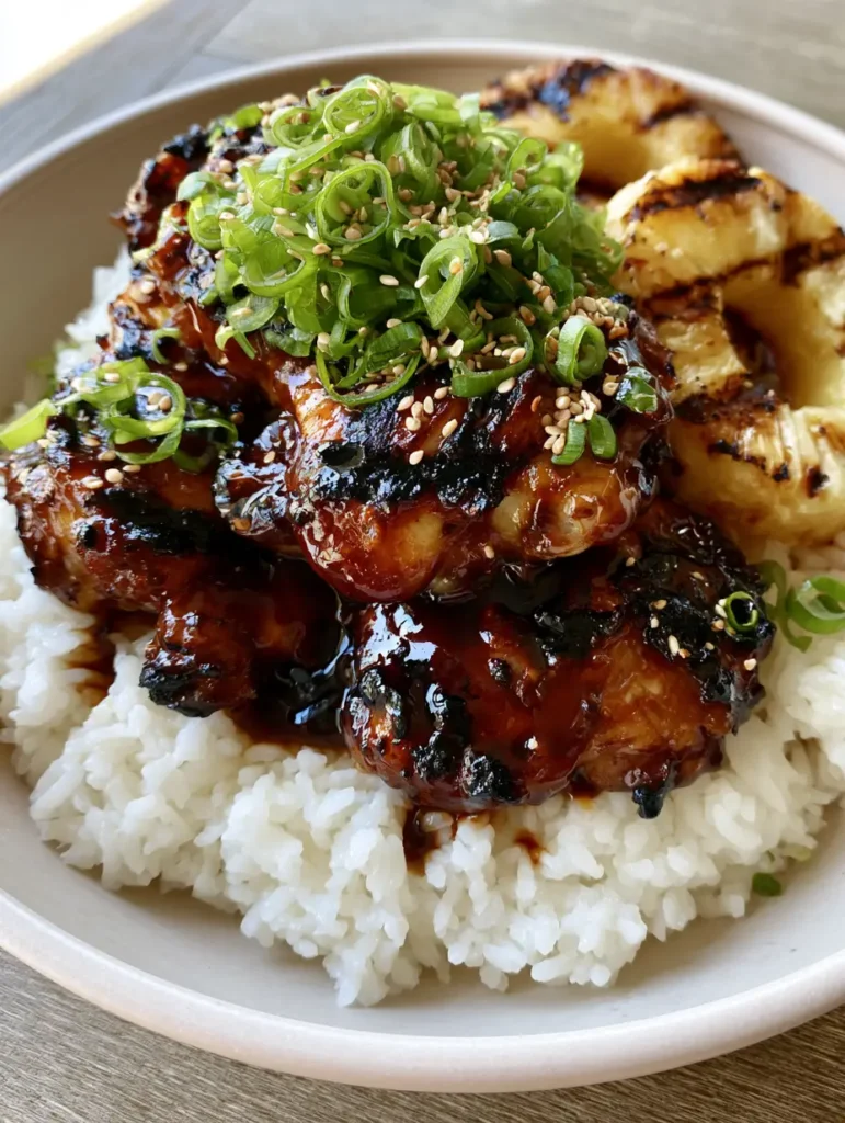 Handheld photo of a Huli Huli Chicken bowl with grilled pineapple rings, scallions, and sesame seeds.