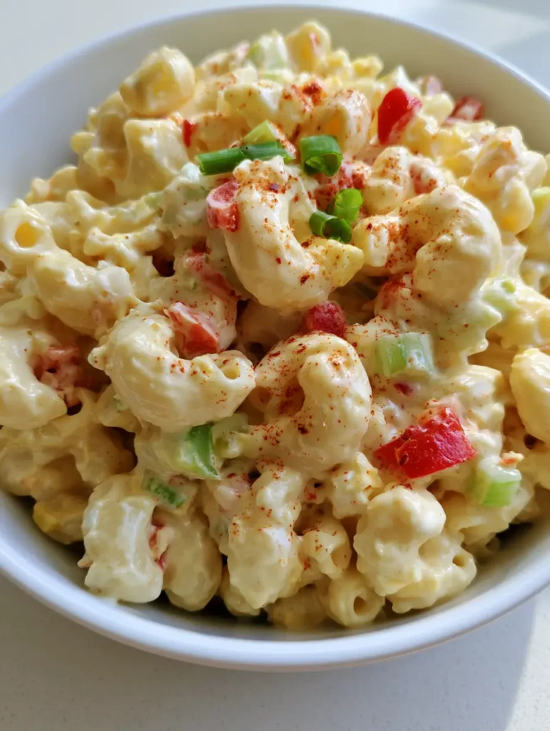 Top-down view of Dolly Parton Macaroni Salad garnished with green onions and paprika.