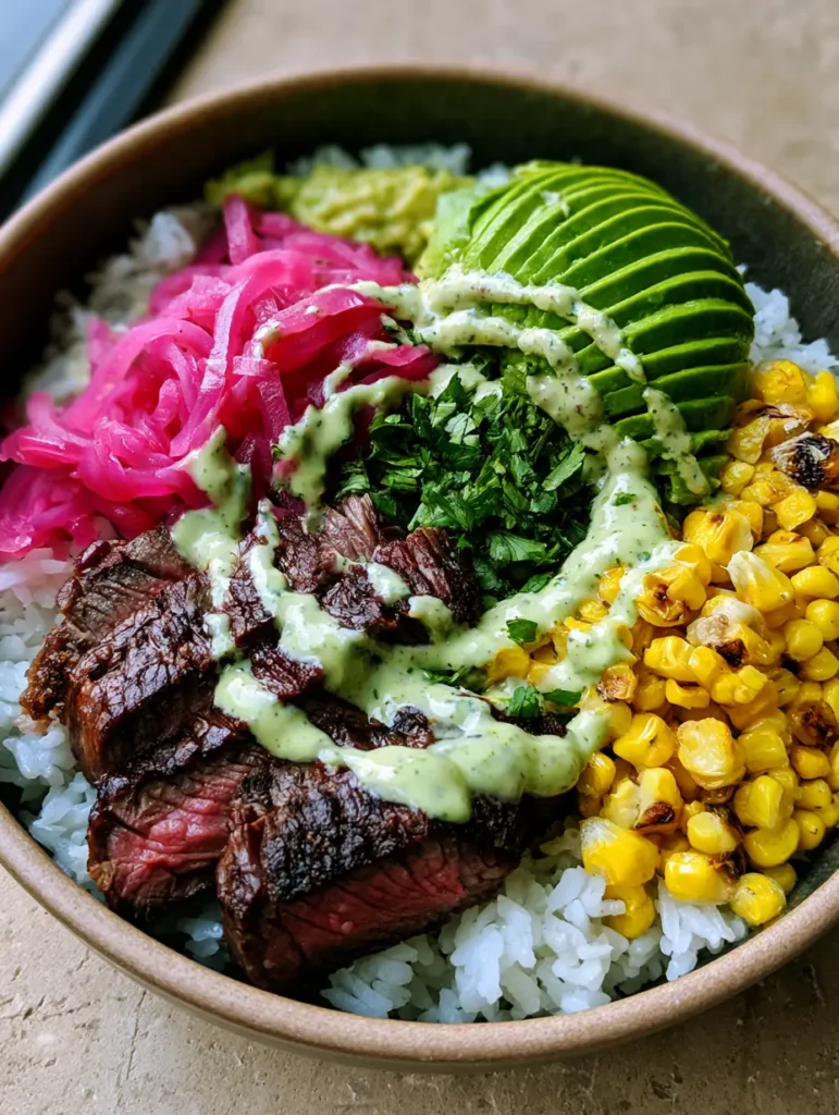 Overhead view of a Steak and Avocado Rice Bowl featuring charred roasted corn and vibrant pink pickled red onions.