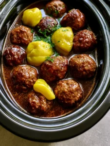 Top-down view of browned beef Mississippi Meatballs in a glossy dark brown gravy with parsley garnish.