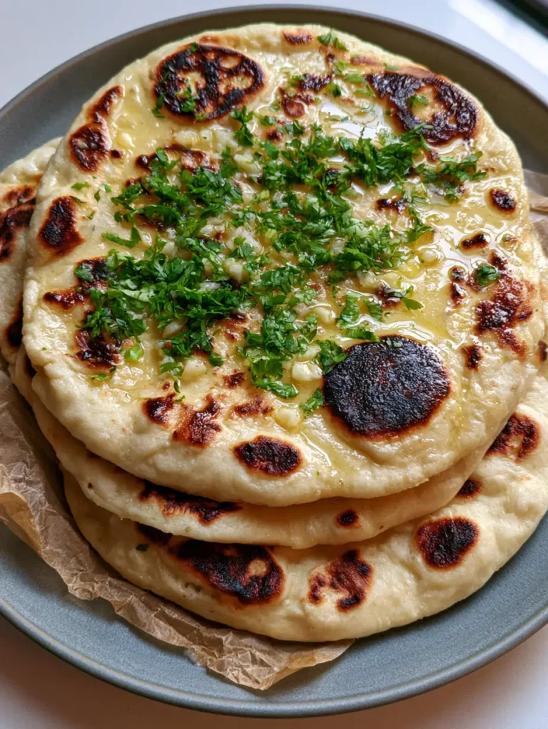 Vegan Gluten-Free Naan: The Ultimate Soft and Garlic-Buttery Flatbread 1 A handheld smartphone style photo of Vegan Gluten-Free Naan on a matte gray ceramic plate.