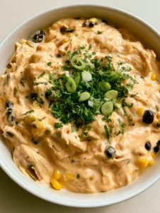 Top-down close-up of shredded chicken in a creamy orange salsa sauce with black beans and corn. (Slow Cooker Fiesta Chicken)