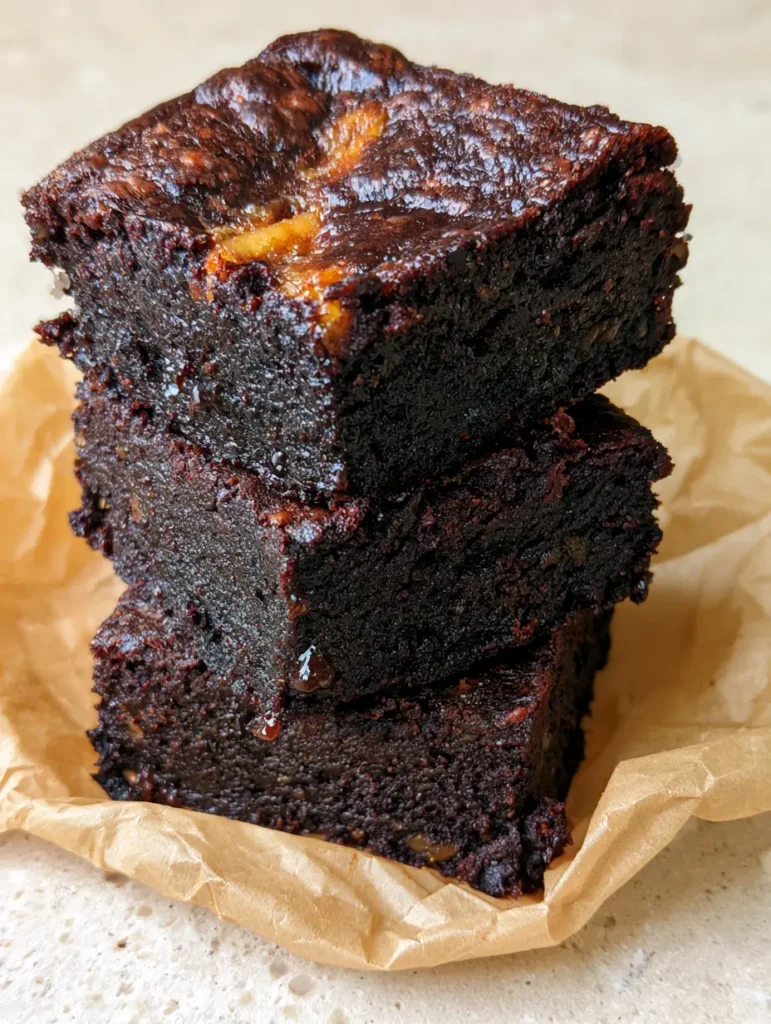 Banana Brownies: The Ultimate Fudgy Dark Chocolate Treat with a Shiny Crackle Crust 1 Top view of square-cut banana brownies with a shiny crackle crust on a stone surface.