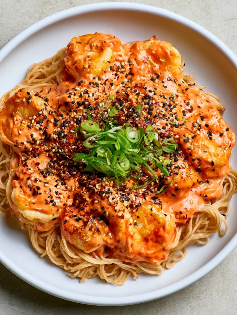 A finished Bang Bang Shrimp Noodle Bowl showing thin wheat noodles and garnished with black and white sesame seeds and fresh scallions.