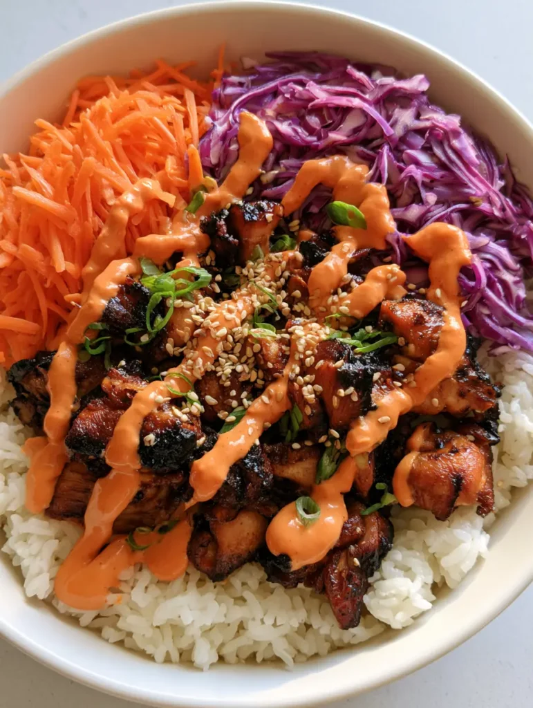 Korean BBQ Chicken Bowls with Creamy Gochujang Drizzle 1 Close up of deeply caramelized chicken pieces with charred edges in a Korean BBQ Chicken Bowl.