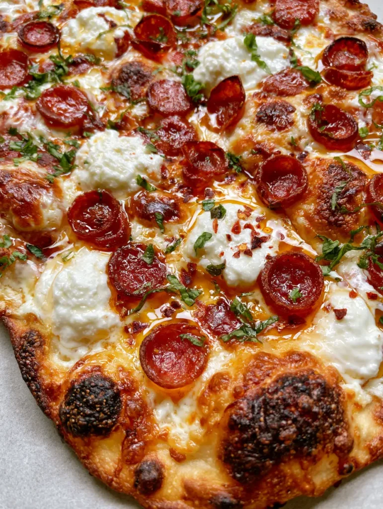 Hot Honey Pepperoni Pizza: The Ultimate Crispy Flatbread Recipe 1 Overhead view of Hot Honey Pepperoni Pizza with fresh basil, ricotta dollops, and red chili flakes.
