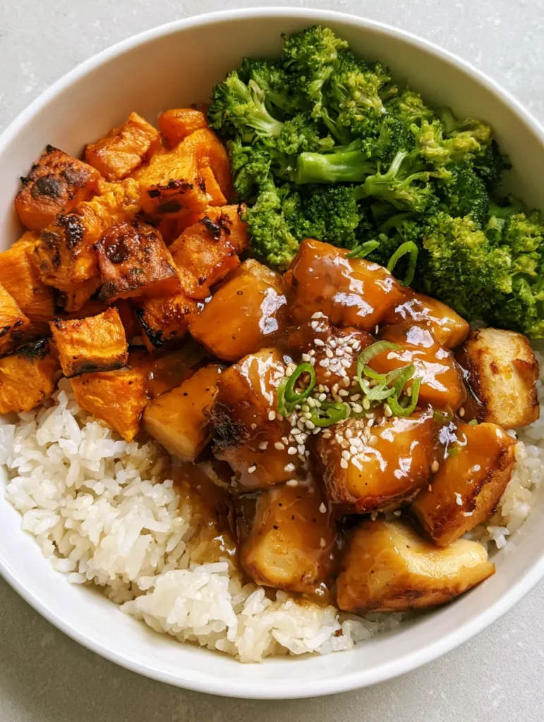 Hot Honey Chicken Bowls with Caramelized Sweet Potatoes and Fluffy Jasmine Rice 1 Top-down handheld photo of a deconstructed hot honey chicken meal with charred sweet potatoes and broccoli. (Hot Honey Chicken Bowls)