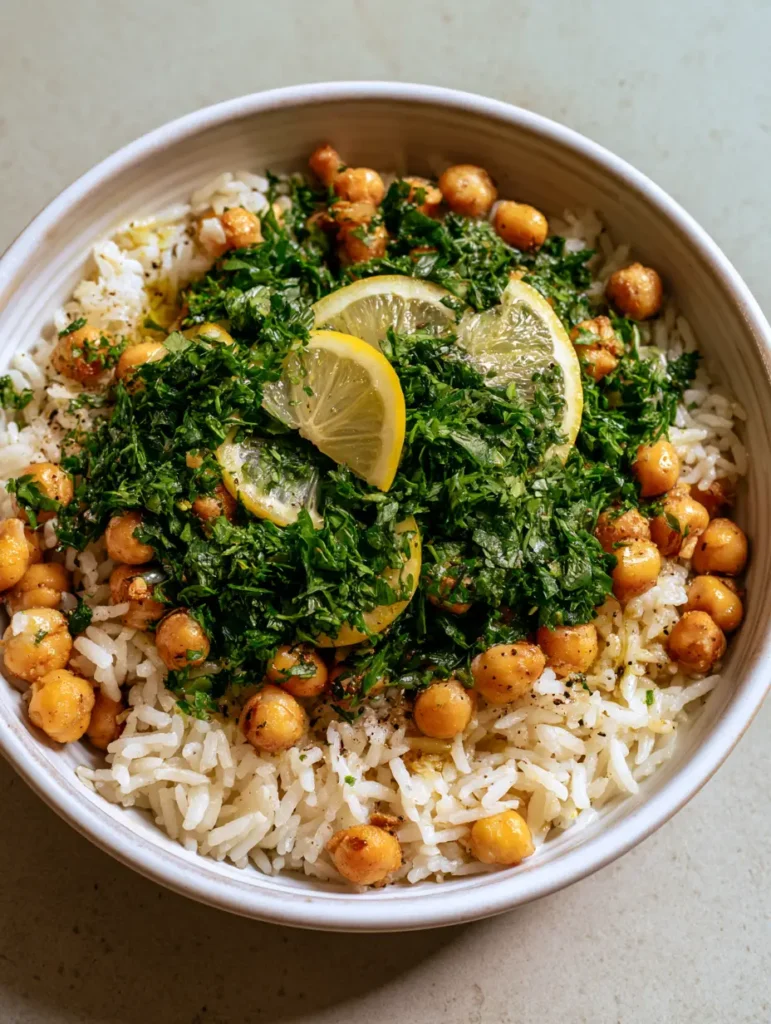 Mediterranean Rice and Beans with Roasted Golden Chickpeas and Lemon 1 Top-down view of a white ceramic bowl filled with Mediterranean Rice and Beans, featuring lemon half-moons and cracked pepper.