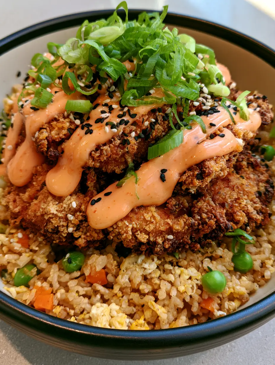 Close-up handheld smartphone photo of craggy crispy breaded chicken chunks with orange chili sauce. (Bang Bang Chicken Fried Rice)